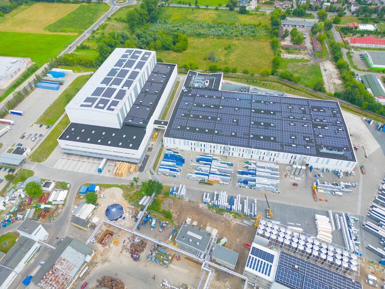Industrie mit niedrigem Kohlenstoff-Fußabdruck. Industrielle Lagerhallen mit Sonnenkollektoren auf dem Dach. Technologiepark und Fabriken von oben.