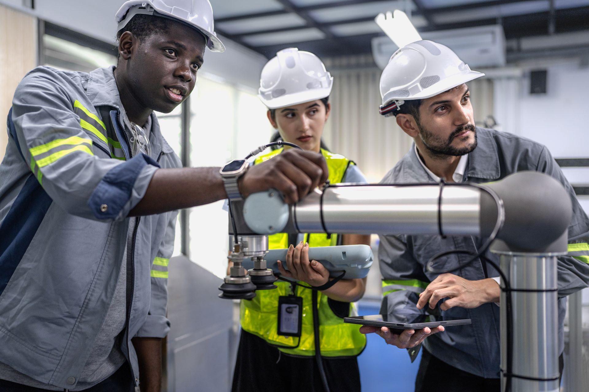 Eine Gruppe verschiedener Personen arbeitet an der Programmierung eines Roboters im Labor für Robotertechnik und Elektronik. Das Ingenieurteam lernt und forscht an einer automatisierten Projektmaschine mit intelligenter mechanischer Steuerung