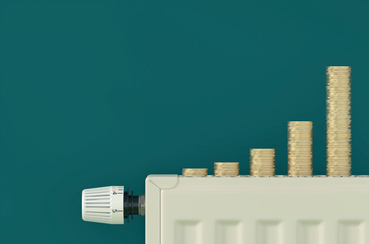 Thermostat an Heizung mit steigenden Münzstapeln - wachsende Heizölpreise Sachsen und steigende Heizkosten im Winter