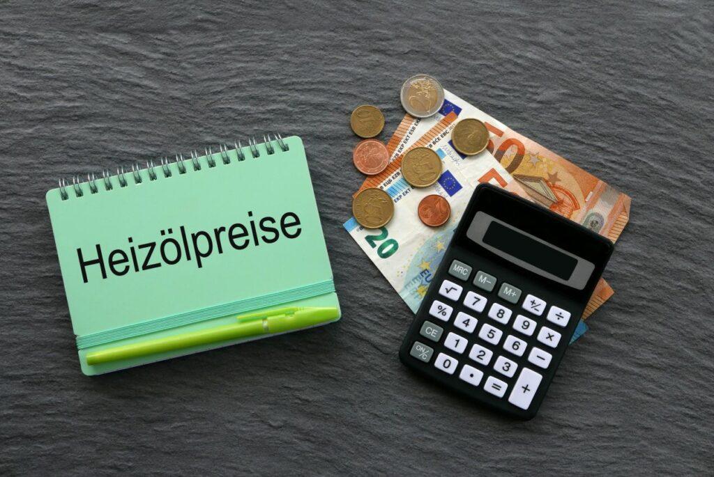 Notizblock mit Aufschrift „Heizölpreise“, Euro-Geld und Taschenrechner auf Steinplatte – aktuelle Heizölpreise in Sachsen