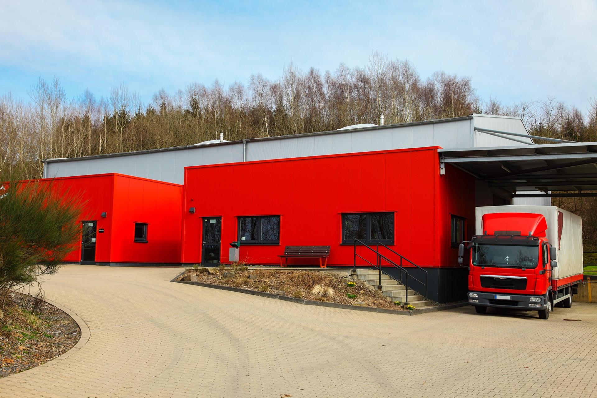 Lkw-Zufahrt zu roter Halle im Lieferbereich | Fahrbahn Markierungen

