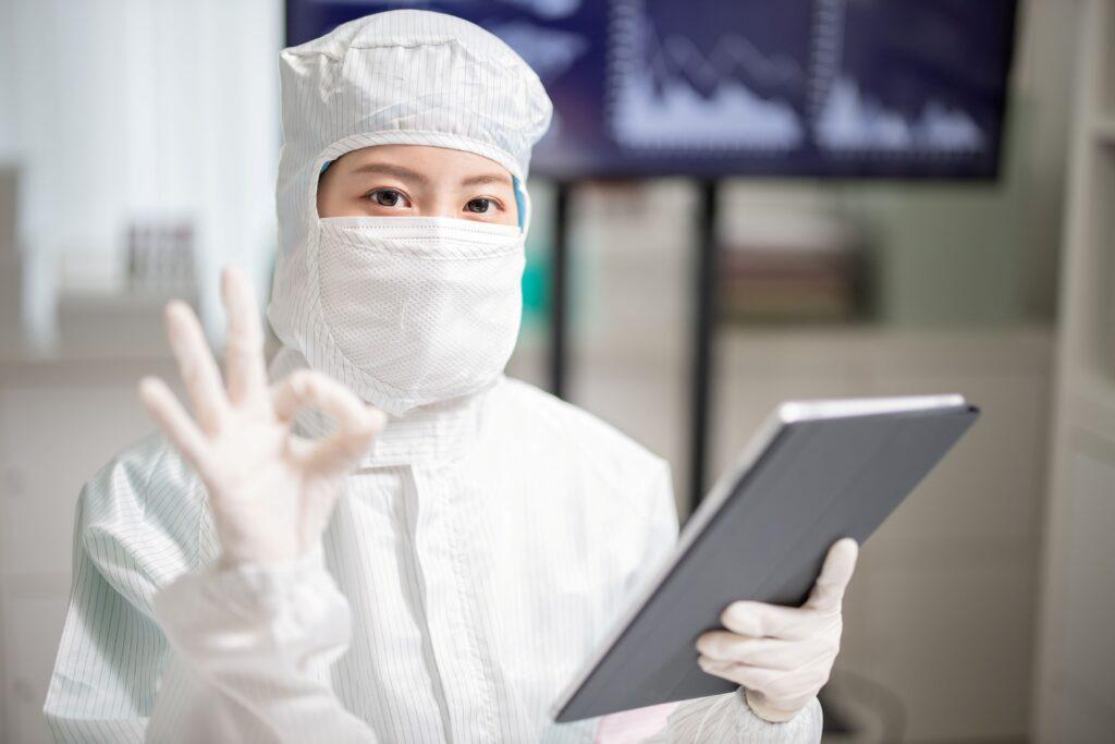 Fachkraft bei der Reinraumreinigung mit Schutzkleidung und Tablet zur Qualitätssicherung