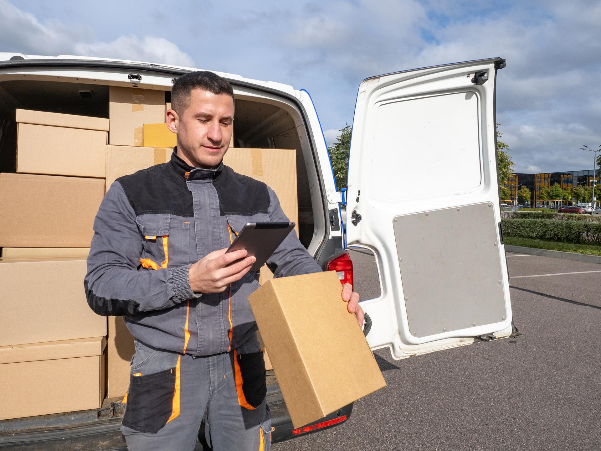 Zusteller prüft Paketdaten vor Lieferfahrzeug | Luftkissenfolie